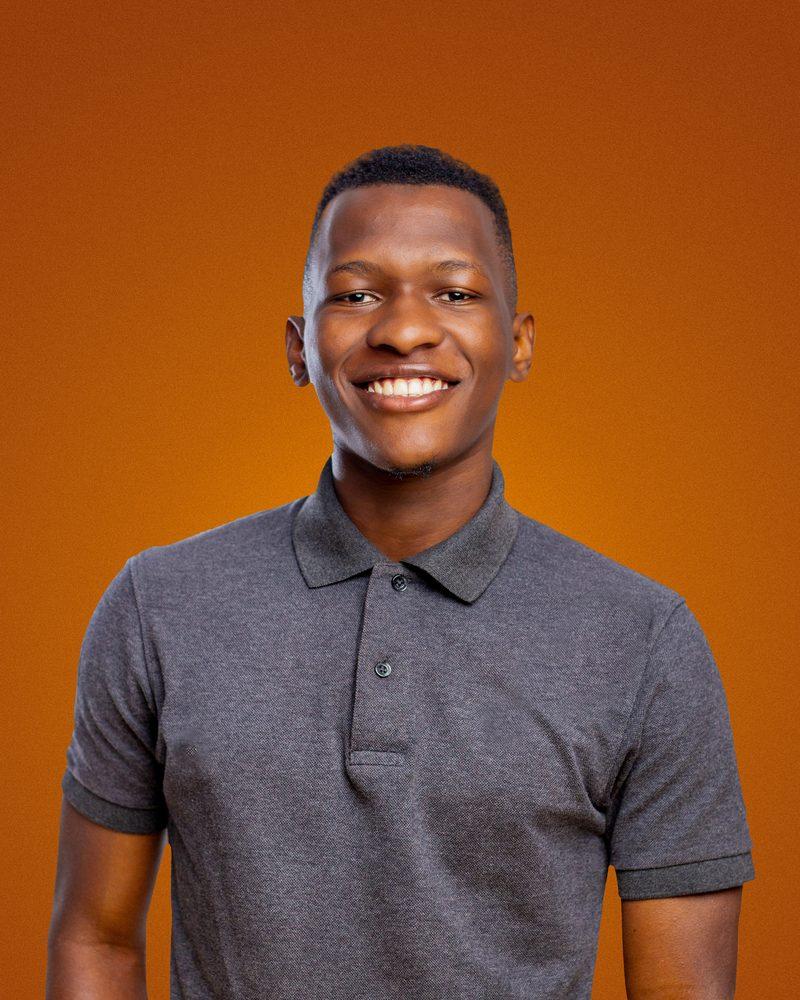 Portrait of Cedric Ahumuza smiling, wearing a grey polo shirt
